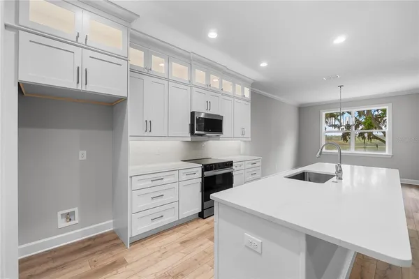 a kitchen with stainless steel appliances kitchen island granite countertop a sink and a stove top oven with wooden floor