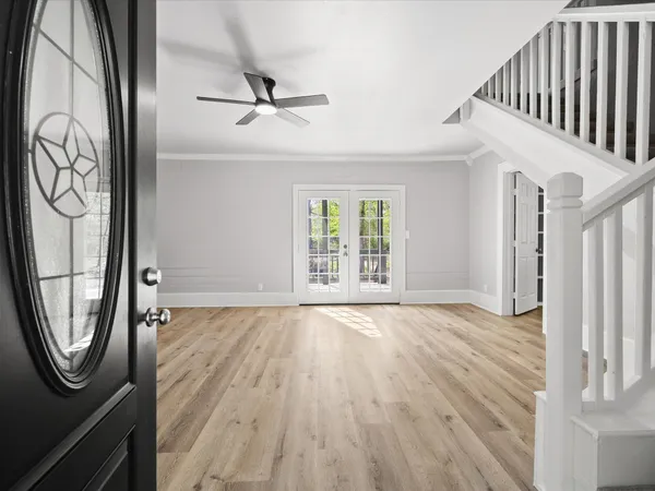 a view of an empty room with wooden floor and a window