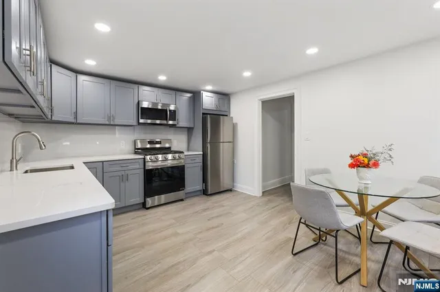 a kitchen with granite countertop a sink cabinets and stainless steel appliances