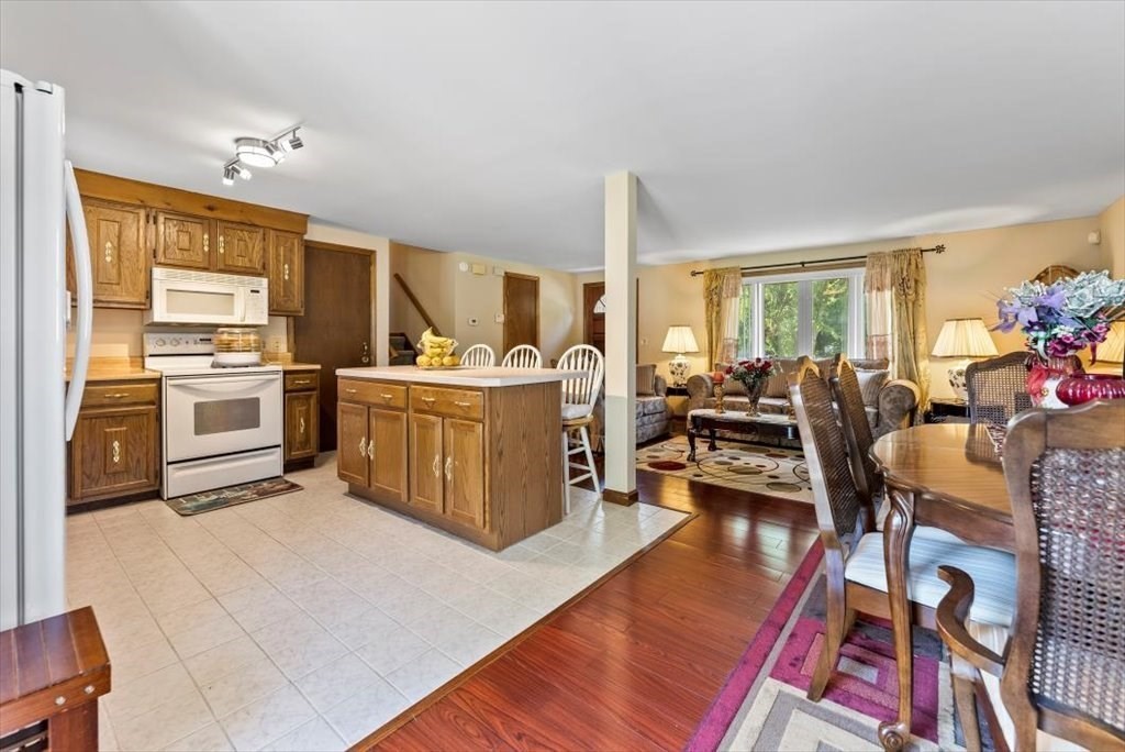 239 Ellendale Circle Springfield, MA 01128 - Photo 14 of 42 a kitchen with stainless steel appliances granite countertop a stove top oven a dining table and chairs with wooden floor