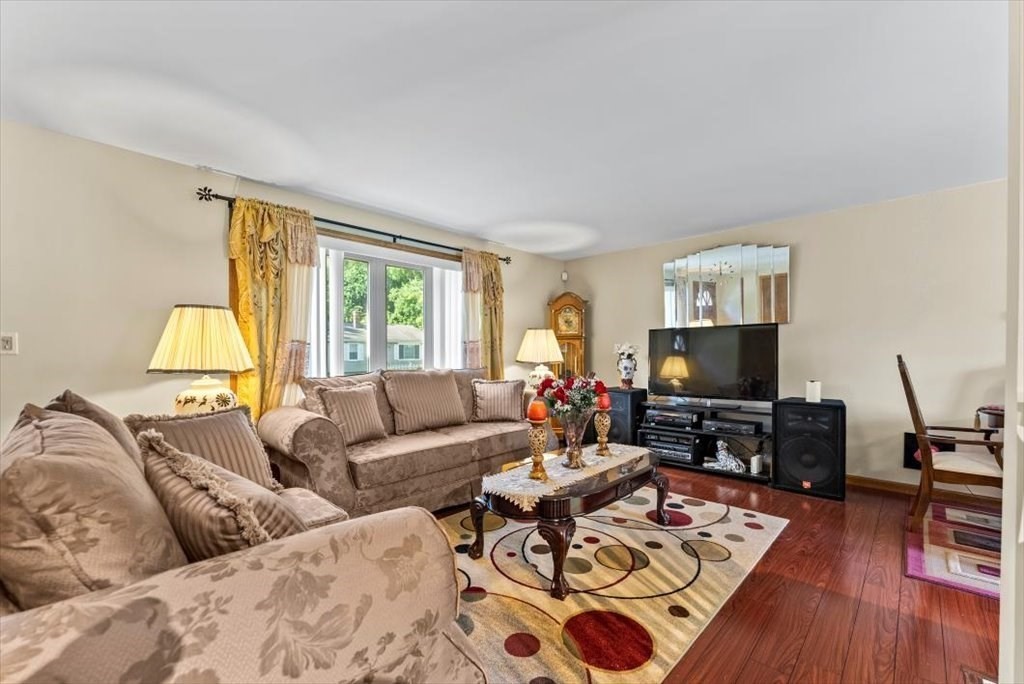 239 Ellendale Circle Springfield, MA 01128 - Photo 6 of 42 a living room with couches a coffee table a lamp and a flat screen tv with wooden floor