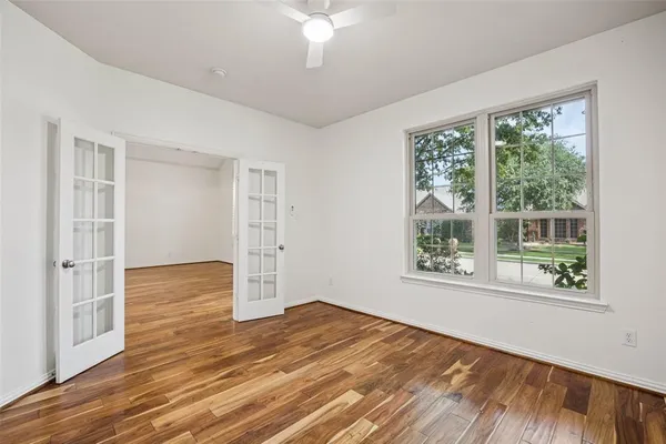 a view of empty room with wooden floor and fan