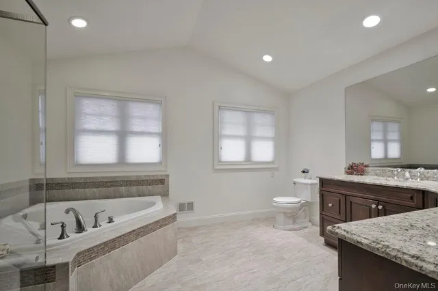 a bathroom with a granite countertop tub a sink and a large window