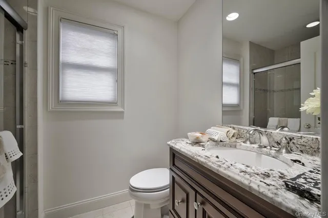 a bathroom with a granite countertop sink a toilet and a mirror