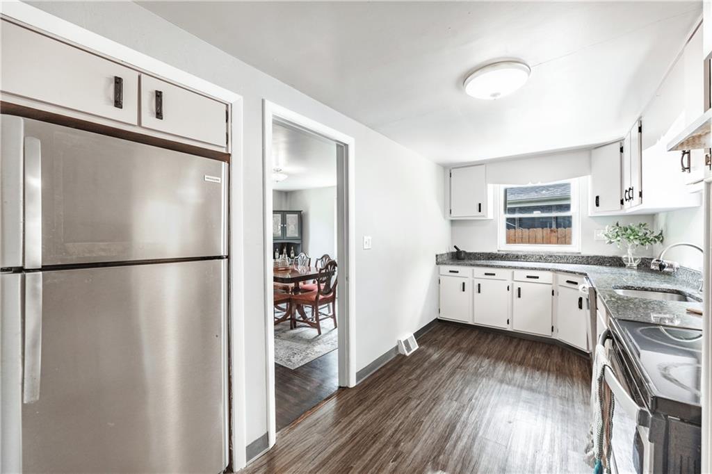 1025 Old Gate Road Pittsburgh, PA 15235 - Photo 6 of 27 a kitchen with stainless steel appliances a refrigerator a stove a sink and white cabinets with wooden floor
