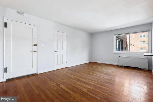 a view of an empty room with wooden floor and windows