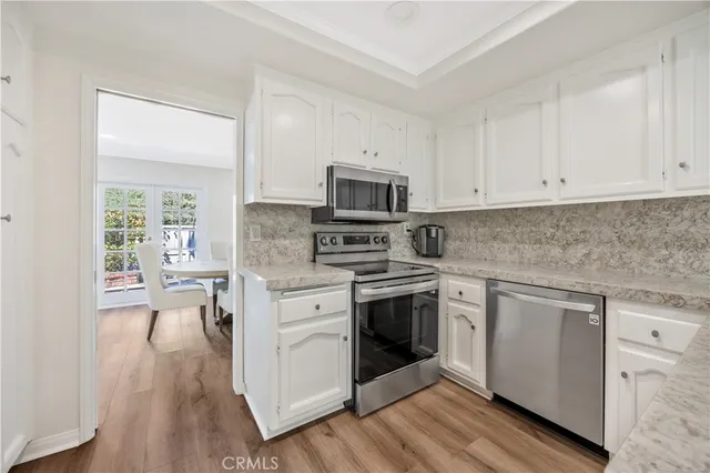 a kitchen with granite countertop white cabinets and stainless steel appliances