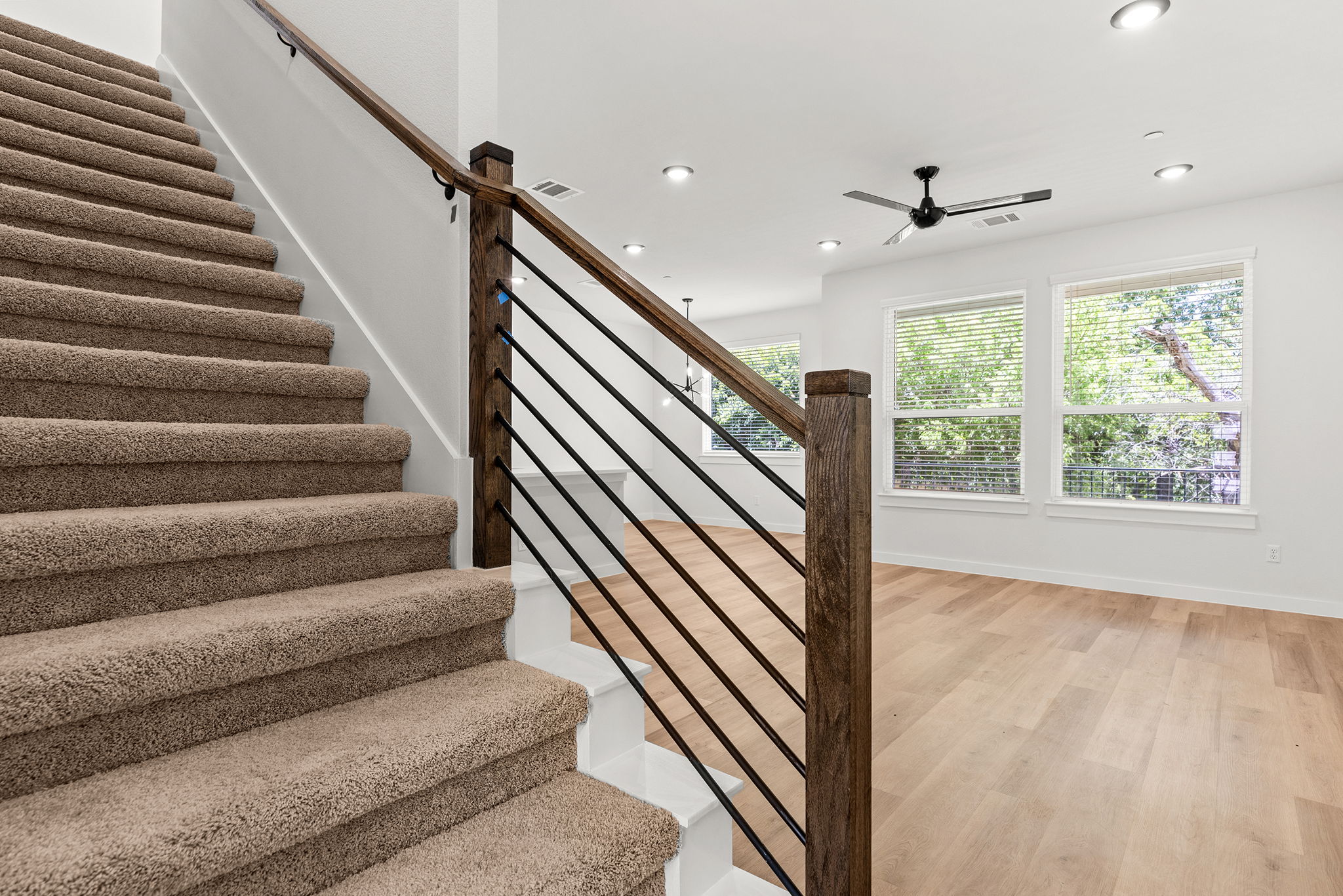 2600 Gattis School Road, Unit 1001 Round Rock, TX 78664 - Photo 18 of 40 A striking modern staircase with dark wood railings and sleek balusters leads to an open-concept living area.