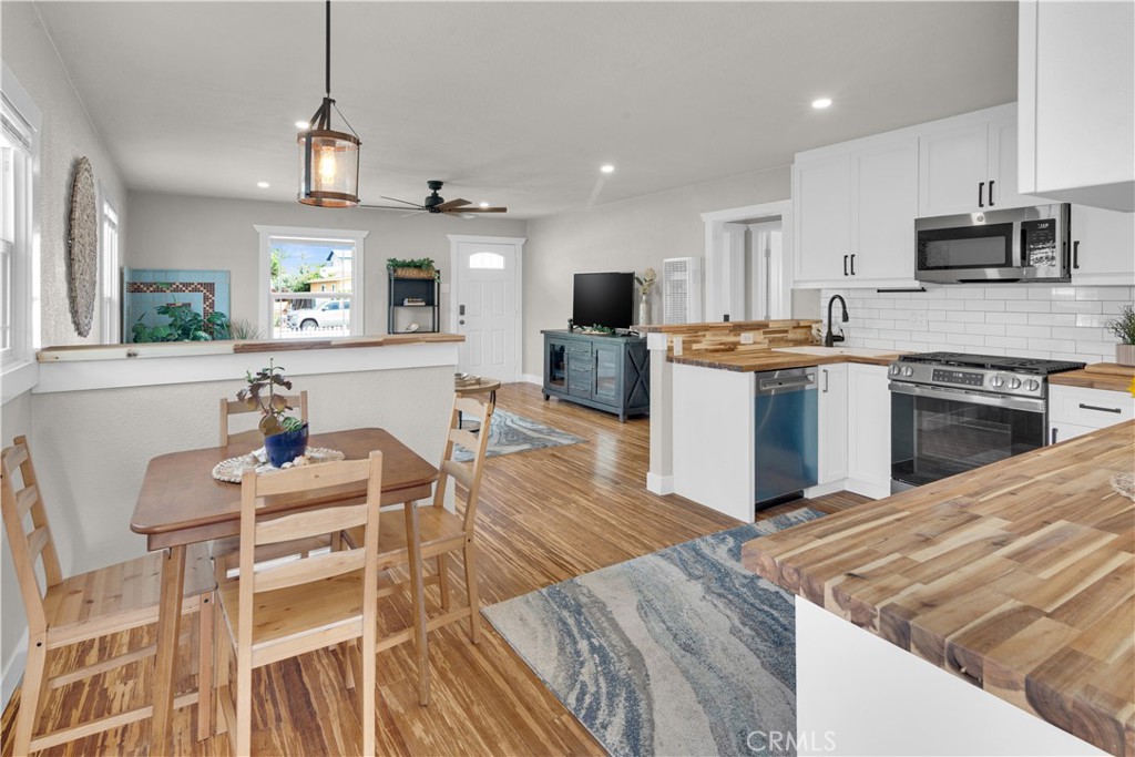 848 Mentone Avenue Grover Beach, CA 93433 - Photo 16 of 33 a living room with stainless steel appliances kitchen island granite countertop a stove top oven a sink a dining table and chairs with wooden floor