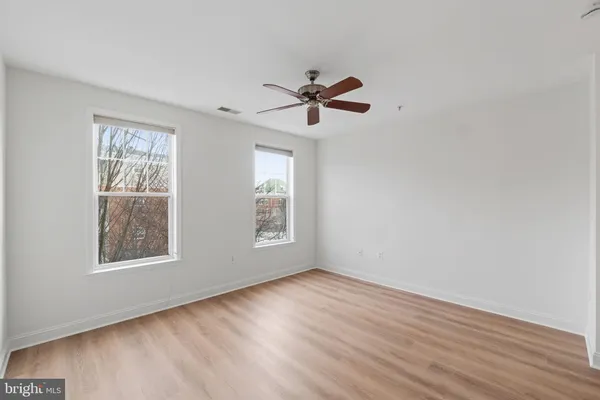 a view of empty room with wooden floor and fan