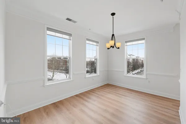 a view of an empty room with chandelier and window
