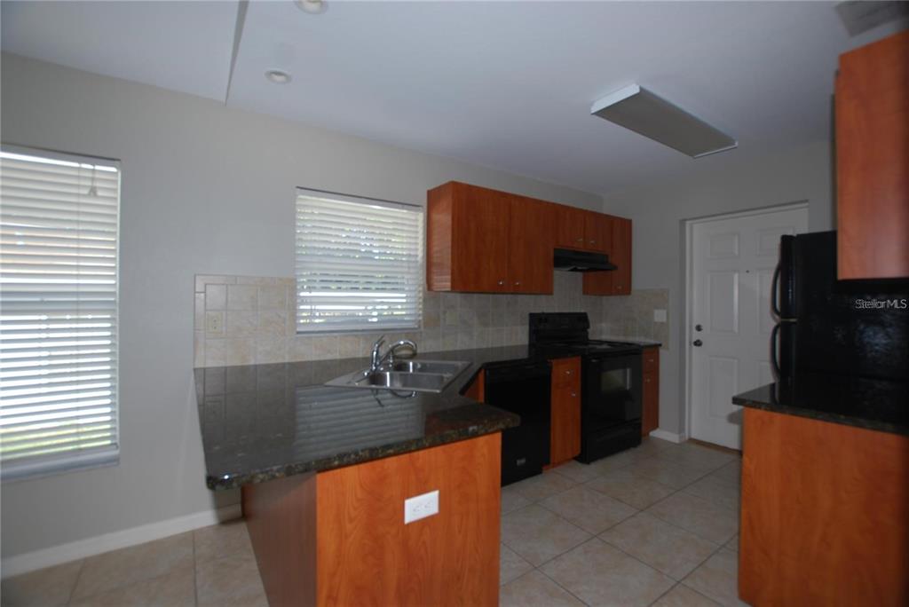 312 East Hibiscus Drive Lakeland, FL 33803 - Photo 4 of 25 a kitchen with granite countertop a stove a sink a refrigerator and a cabinets