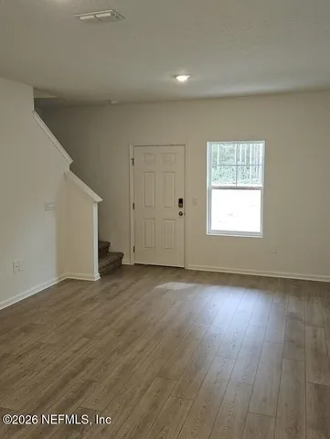 an empty room with wooden floor and windows