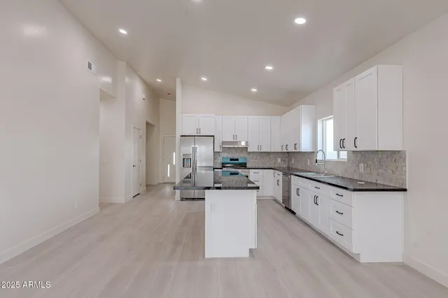 a kitchen with stainless steel appliances granite countertop a sink stove and refrigerator