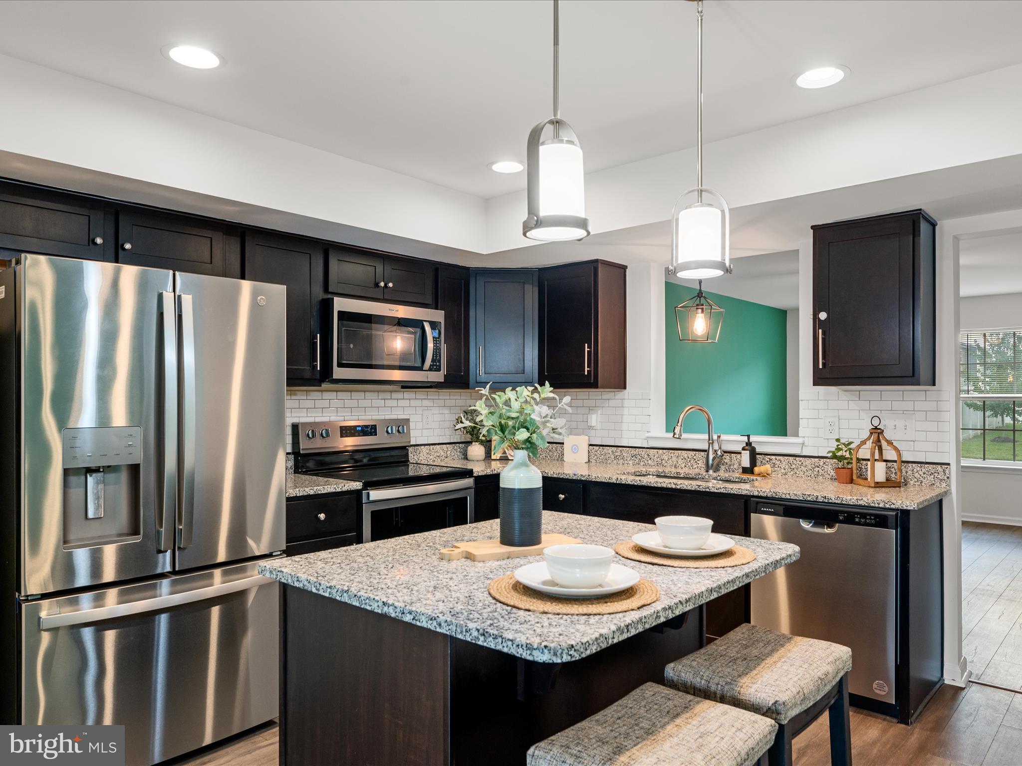 a kitchen with stainless steel appliances granite countertop a sink refrigerator and microwave