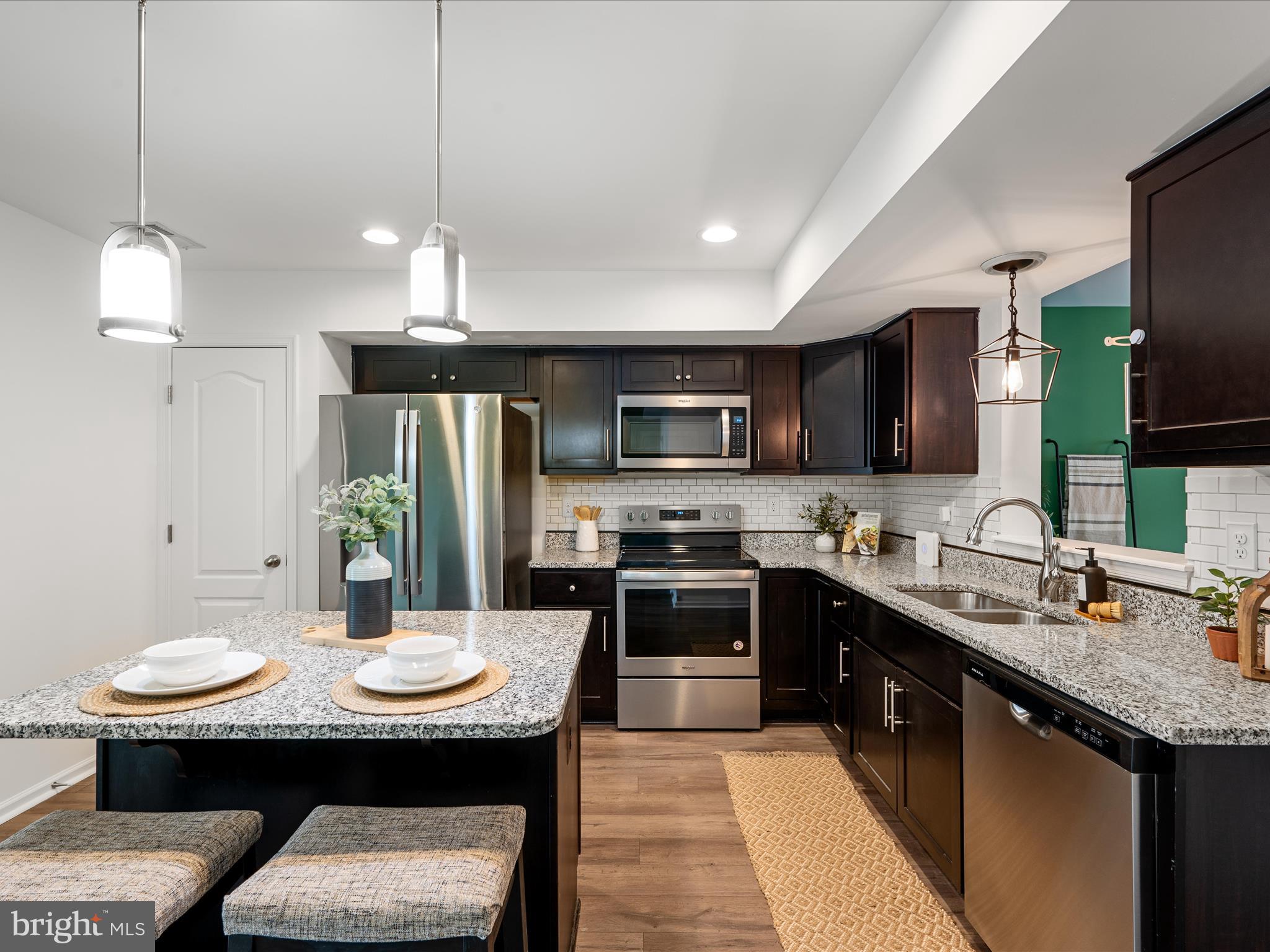 576 Thumper Drive Ranson, WV 25438 - Photo 11 of 37 a kitchen with stainless steel appliances kitchen island granite countertop a sink a stove a refrigerator a kitchen island with chairs and cabinets