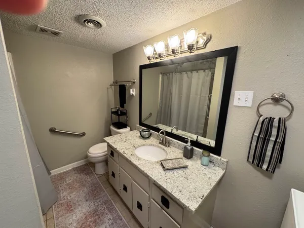a bathroom with a granite countertop sink a toilet and mirror