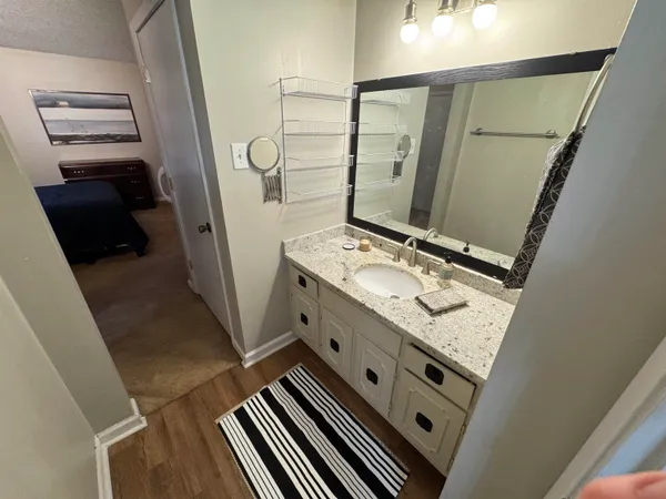 a bathroom with a granite countertop sink a mirror and shower