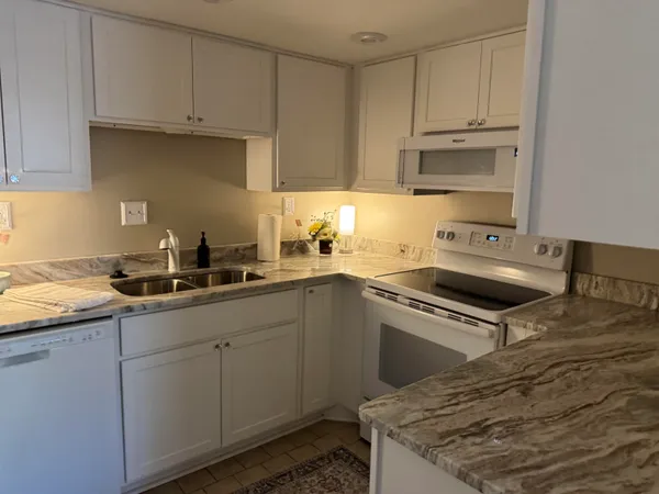 a kitchen with granite countertop a sink a stove and cabinets