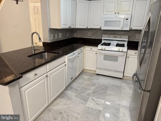 a kitchen with granite countertop white cabinets and white appliances