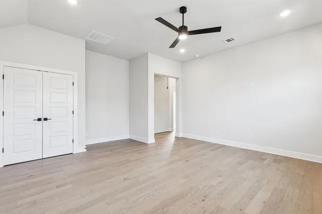 an empty room with wooden floor and ceiling fan