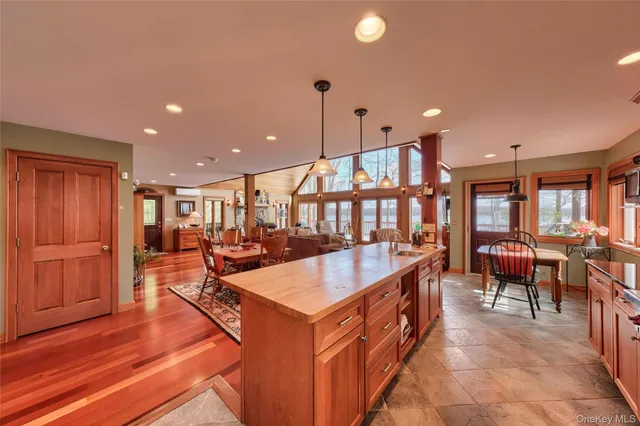 a large living room with stainless steel appliances kitchen island granite countertop a large kitchen island a stove a sink a dining table and chairs with wooden floor