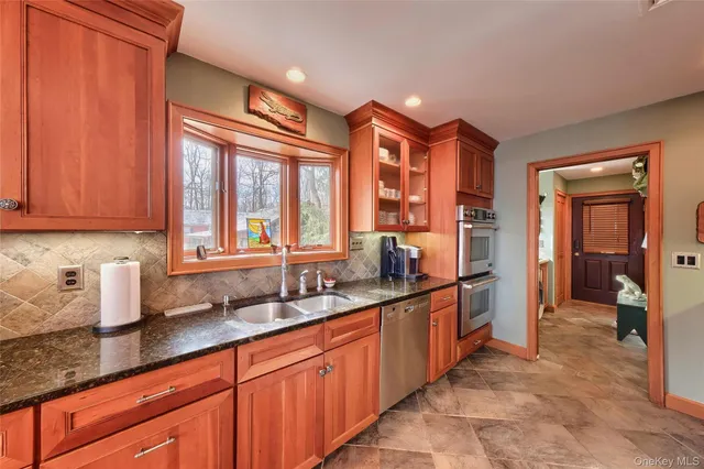 a large kitchen with stainless steel appliances granite countertop a sink and dishwasher a refrigerator with wooden cabinets