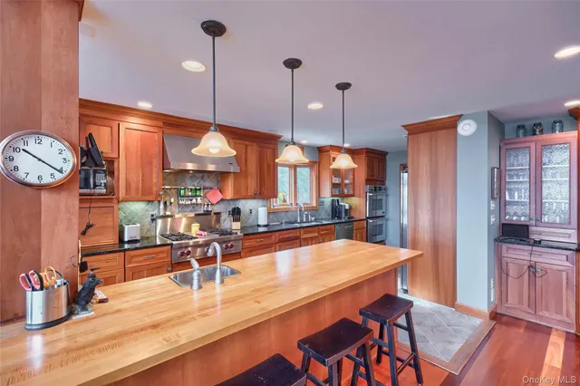 a kitchen with stainless steel appliances kitchen island granite countertop a table chairs in it and wooden floors