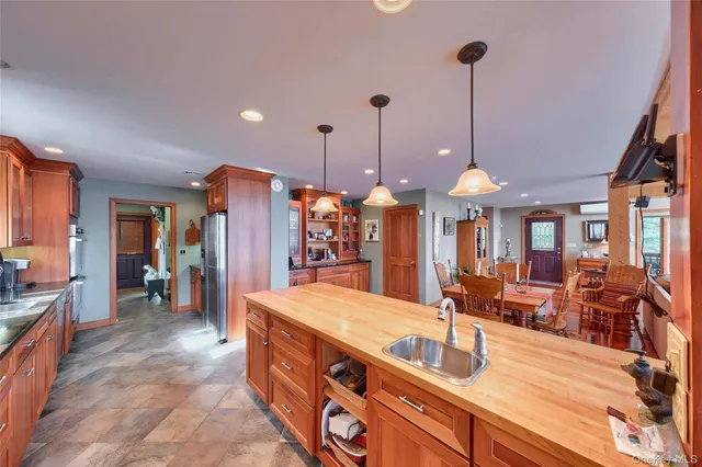 a view of a kitchen with kitchen island a large counter top space a sink stainless steel appliances and living room view