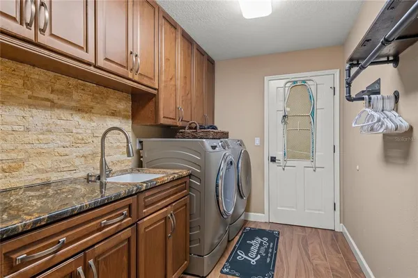 a kitchen with stainless steel appliances granite countertop a refrigerator a sink dishwasher a stove and white cabinets with wooden floor