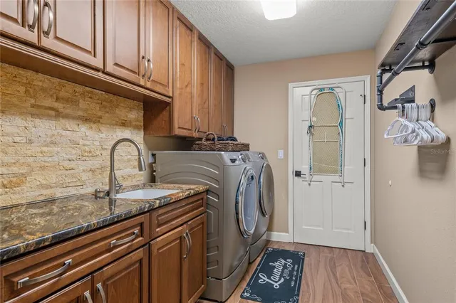 a kitchen with stainless steel appliances granite countertop a refrigerator a sink dishwasher a stove and white cabinets with wooden floor