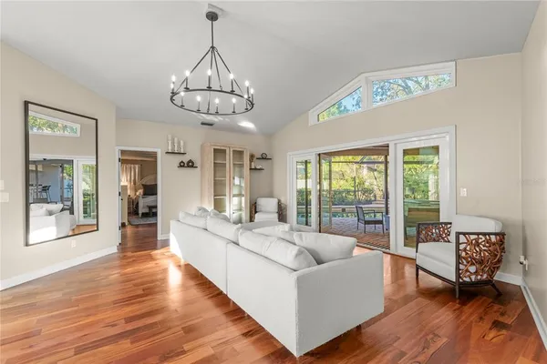 a dining room with wooden floor a chandelier a wooden table and chairs