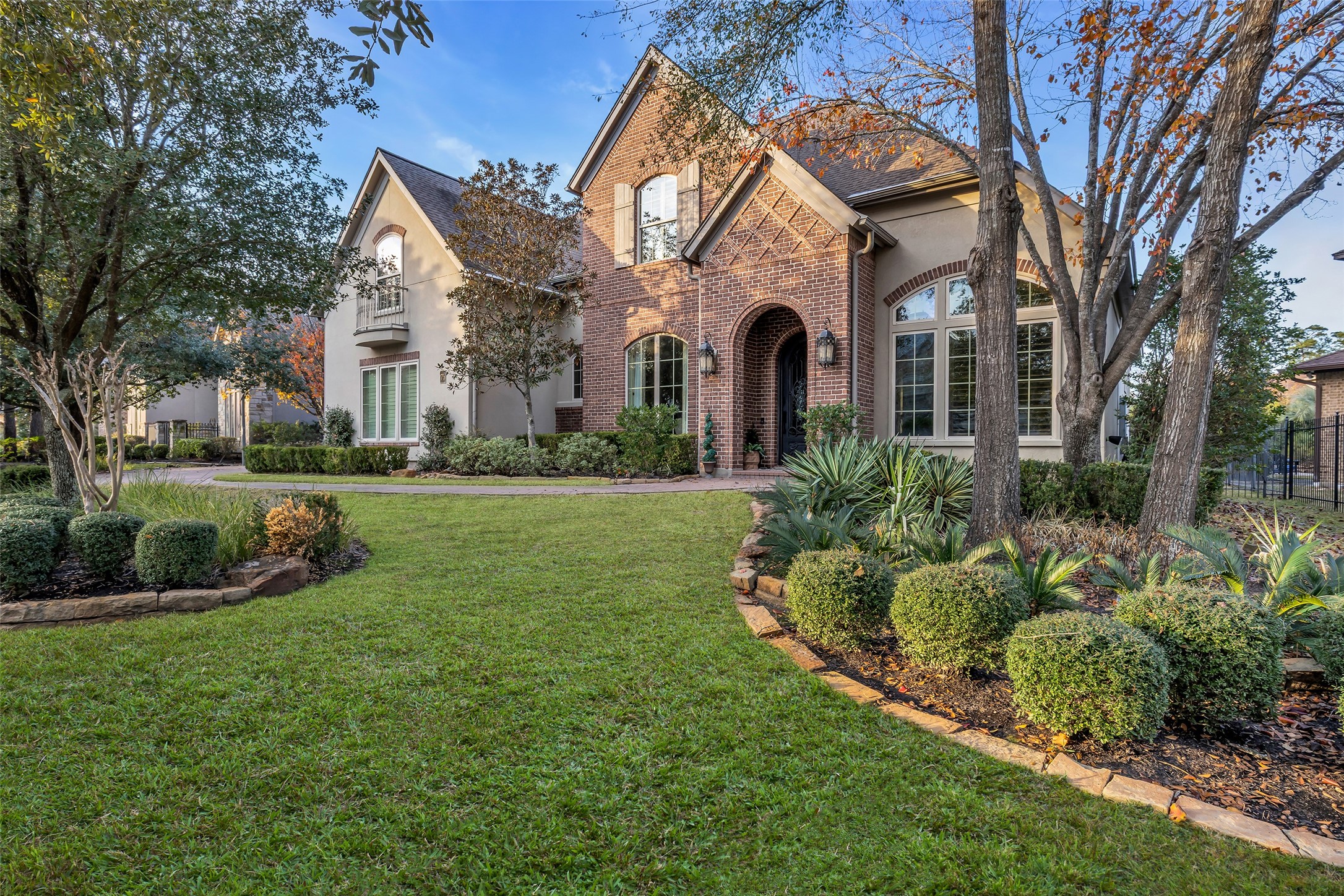 a view of a big house with a big yard and potted plants and large trees