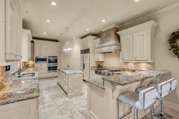 a kitchen with stainless steel appliances granite countertop a stove top oven a sink a refrigerator and white cabinets