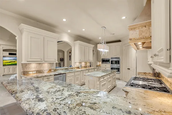 a large kitchen with granite countertop a large stove a sink and cabinets