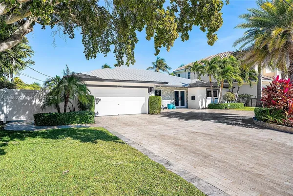 a front view of a house with a garden and palm trees