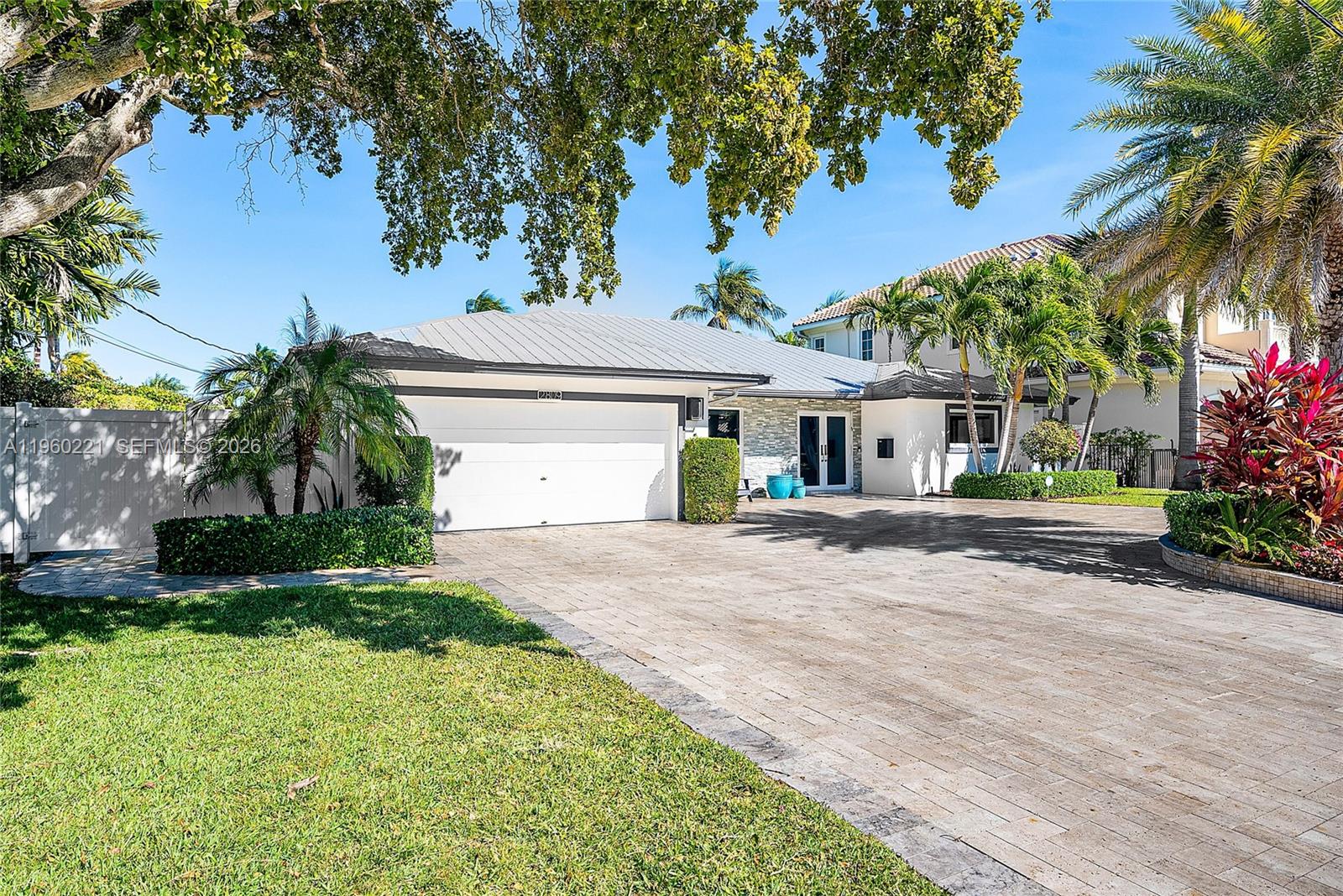 2809 Northeast 32nd Street Lighthouse Point, FL 33064 - Photo 4 of 48 a front view of a house with a garden and palm trees