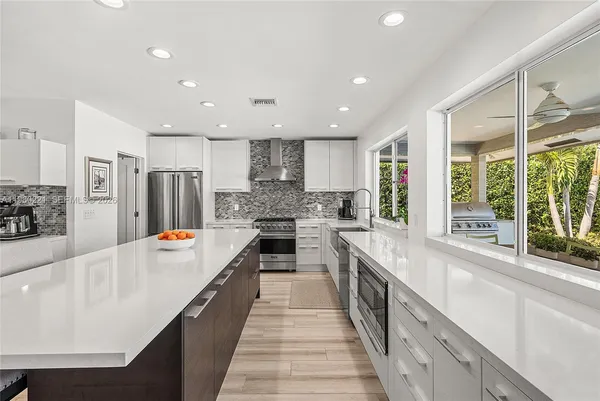 a large kitchen with stainless steel appliances a large counter top a stove a refrigerator a sink and a refrigerator