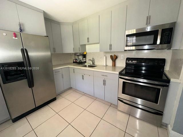 10975 Southwest 107th Street, Unit 110 Miami, FL 33176 - Photo 6 of 26 a kitchen with cabinets stainless steel appliances and a sink