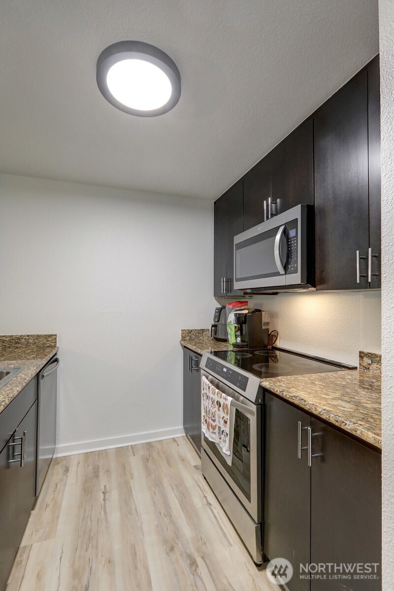 9806 28th Avenue Southwest, Unit A201 Seattle, WA 98126 - Photo 6 of 14 a kitchen with stainless steel appliances granite countertop a stove a sink and a microwave
