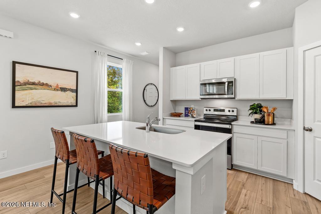 10700 Waterfield Road Jacksonville, FL 32210 - Photo 8 of 39 a kitchen with a table chairs a stove a microwave and cabinets