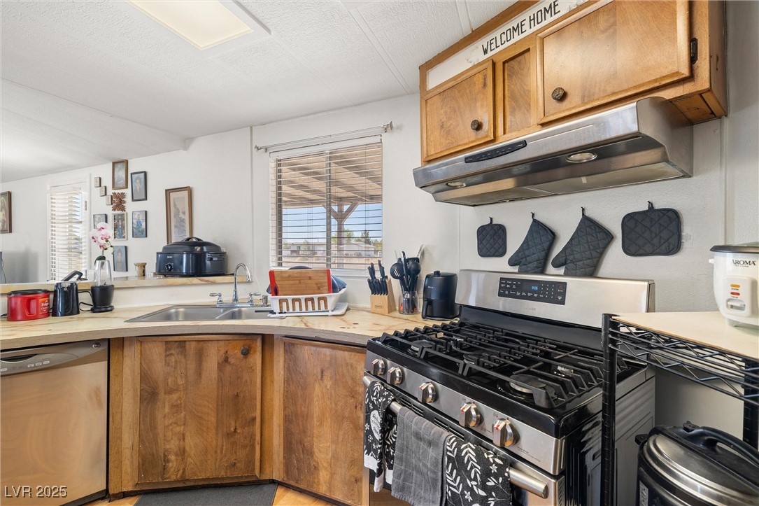 3581 West Dyer Road Pahrump, NV 89048 - Photo 11 of 31 Kitchen featuring appliances with stainless steel finishes, healthy amount of natural light, under cabinet range hood, and light countertops