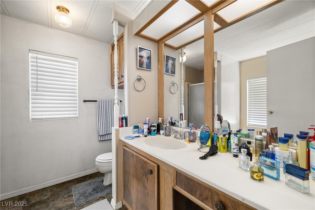3581 West Dyer Road Pahrump, NV 89048 - Photo 17 of 31 Full bath featuring vanity, a stall shower, healthy amount of natural light, and stone finish floors