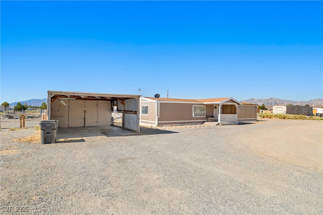 3581 West Dyer Road Pahrump, NV 89048 - Photo 2 of 31 Manufactured / mobile home featuring a mountain view, a detached carport, and driveway