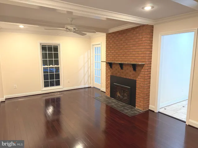 a view of a big room with a chandelier fan and wooden floor