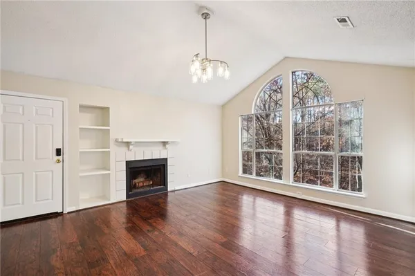 an empty room with wooden floor fireplace and windows