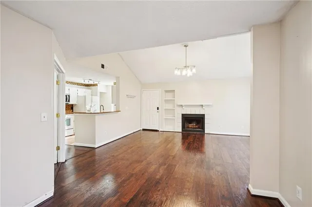 an empty room with wooden floor fireplace and windows