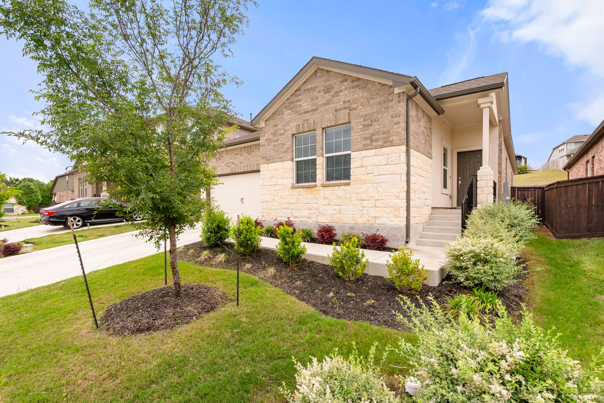 View of front of property featuring concrete driveway, stone siding, and an attached garage