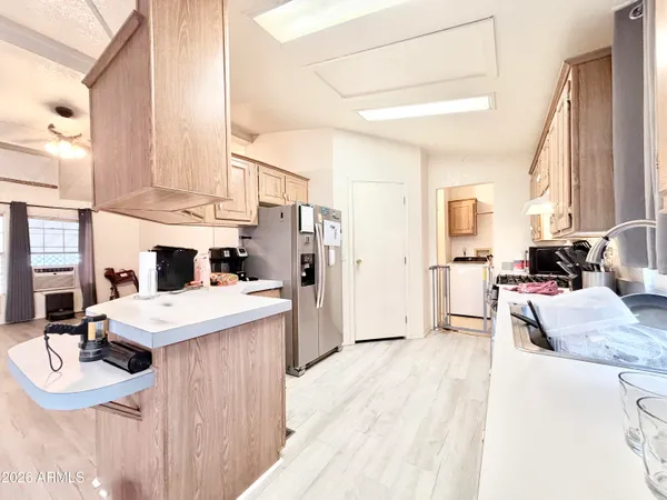 a kitchen with granite countertop a stove a sink dishwasher a refrigerator and cabinets with wooden floor