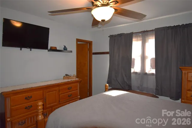 a bedroom with a bed and a flat tv screen on dresser